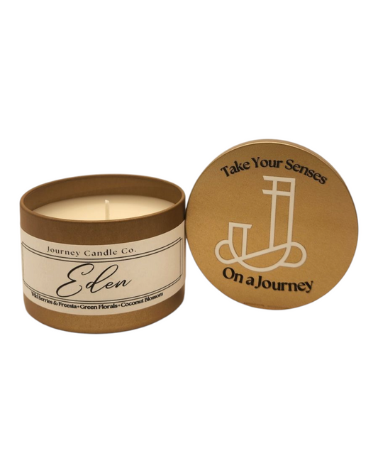 Eden 3oz gold candle tin with pink sugar, strawberry, and hibiscus scent, paired with branded satin travel bag.