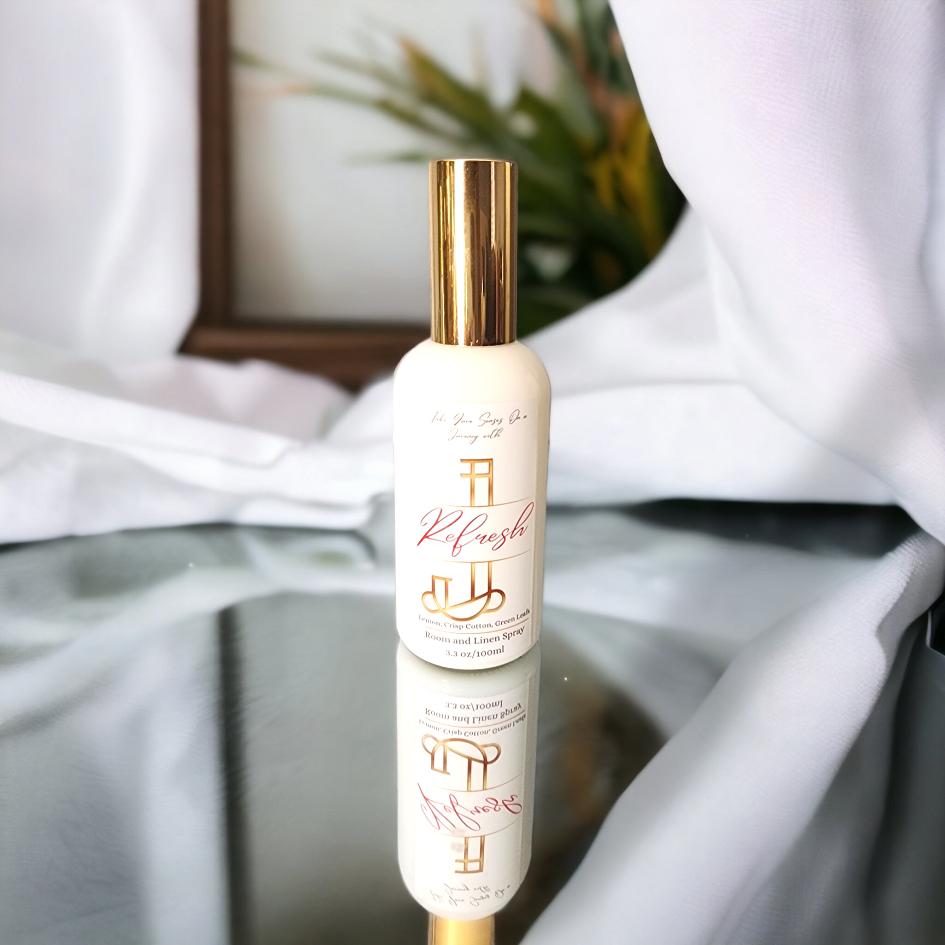 Refresh room and linen spray in a white jar with a sleek gold lid, featuring bright lemon, crisp cotton, and green leaves – a fresh, uplifting home fragrance mist